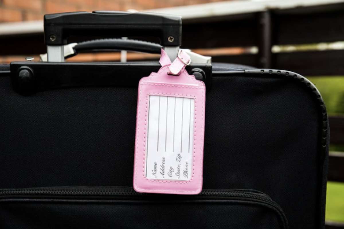 Donna valigia targhetta Una pratica diffusa tra i viaggiatori è quella di legare un nastro colorato o applicare targhette personalizzate ai propri bagagli