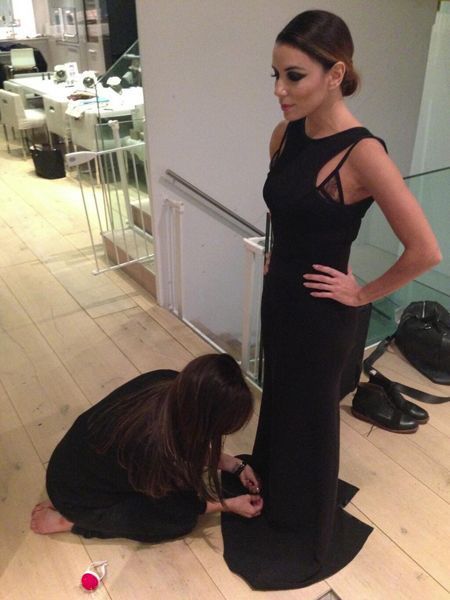 Victoria Beckham inginocchiata a sistemare l'abito di Eva Longoria