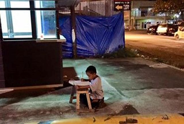 Bambino che fa i compiti alla luce di un lampione: foto simbolo sul web