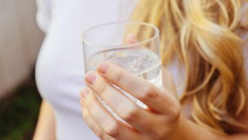 donna tiene in mano un bicchiere di acqua