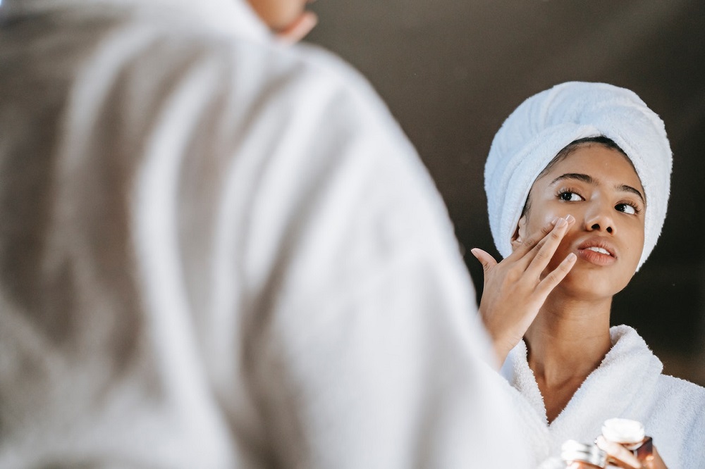 giovane donna si stende una crema sul viso