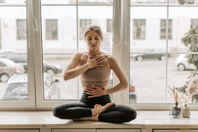 giovane donna pratica yoga con dei leggings a vita alta neri